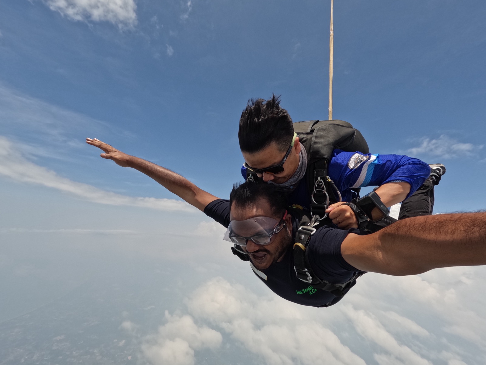 Dheeraj in tandem freefall over Rayong, Thailand, arms spread, clouds below.